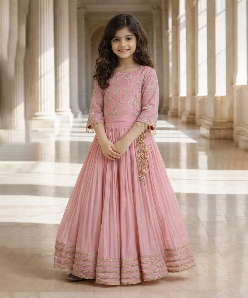 Young girl in a pink traditional outfit standing in a grand hall with columns.
