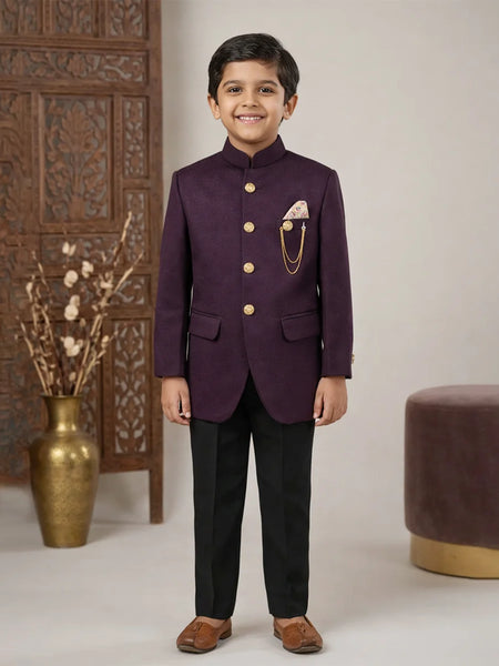 Young boy in a formal purple suit standing in a decorated room with a vase and decorative wall.
