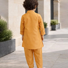 Child in a mustard yellow outfit standing on a stone pathway with architectural elements in the background.