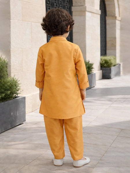 Child in a mustard yellow outfit standing on a stone pathway with architectural elements in the background.