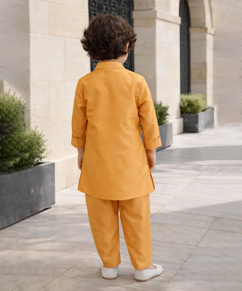 Child in a mustard yellow outfit standing on a stone pathway with architectural elements in the background.
