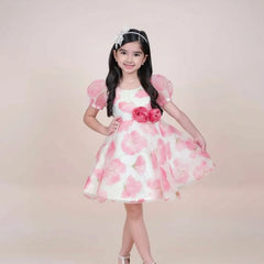 girl in a pink floral dress posing against a plain background