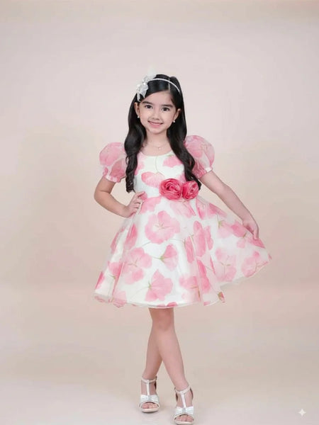 girl in a pink floral dress posing against a plain background