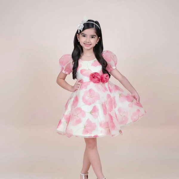 girl in a pink floral dress posing against a plain background