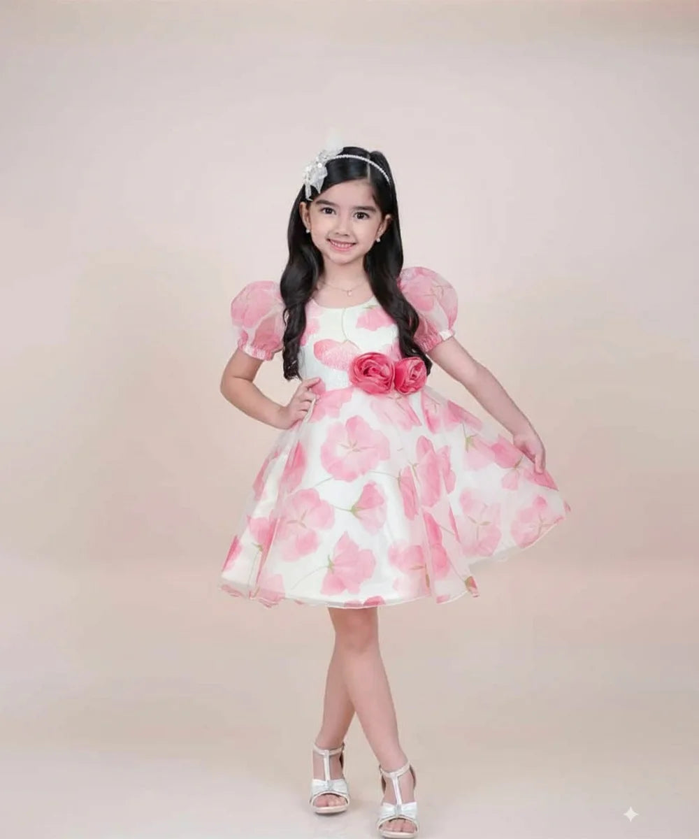 girl in a pink floral dress posing against a plain background