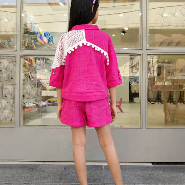 Person wearing a bright pink outfit with white accents in front of a store entrance.