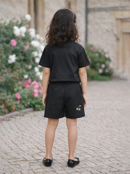Person wearing a black outfit with embroidered shorts in an outdoor setting.