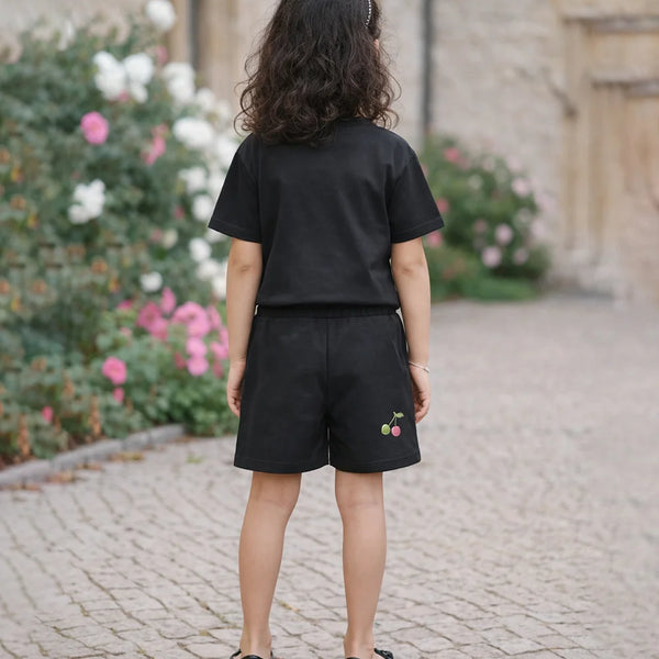 Person wearing a black outfit with embroidered shorts in an outdoor setting.