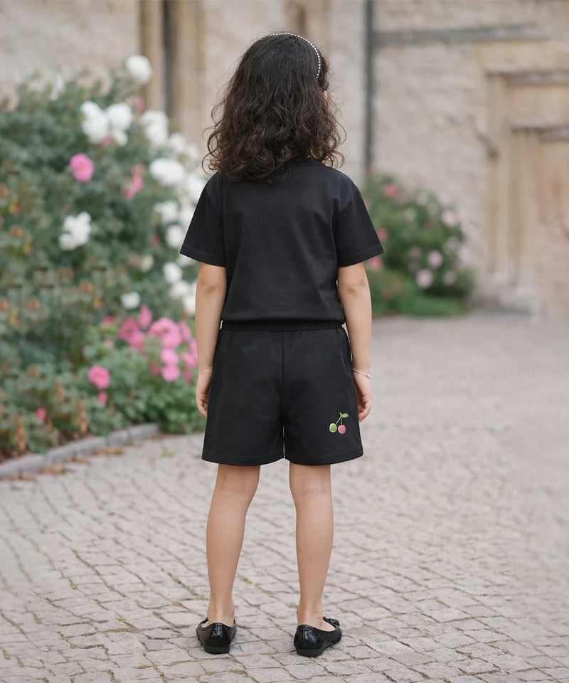 Person wearing a black outfit with embroidered shorts in an outdoor setting.