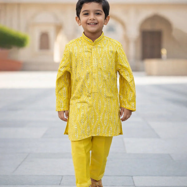 Child wearing a yellow traditional outfit standing in an outdoor setting