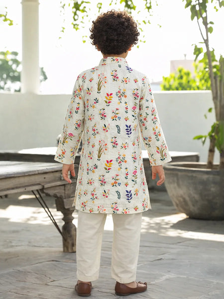 Child wearing a floral embroidered kurta with white pants outdoors.
