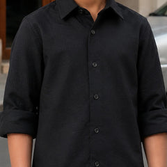Person wearing a black button-up shirt with rolled-up sleeves.