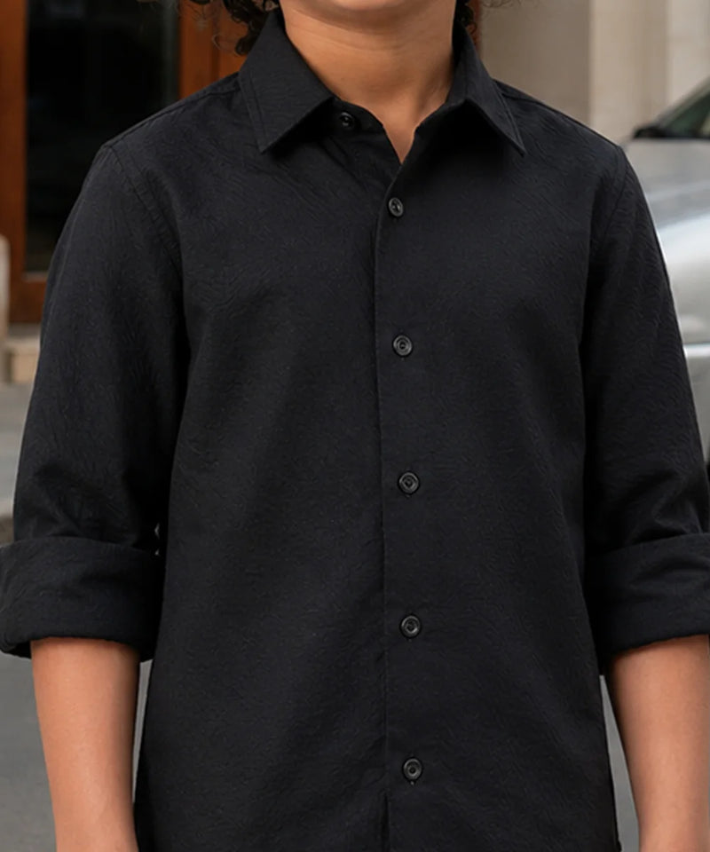 Person wearing a black button-up shirt with rolled-up sleeves.