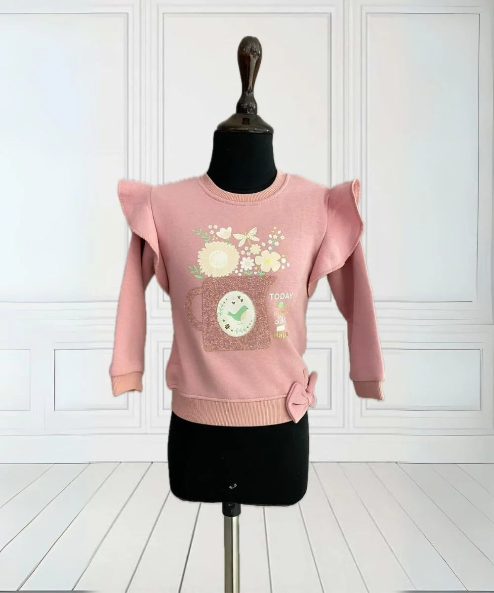 It's an onion pink Colored sweatshirt for girls that comes with a small ruffle detailing on sleeves. It features a beautiful floral print, embossed mug look and 
