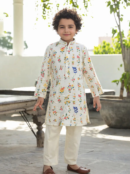 Child wearing a floral embroidered kurta with white pants outdoors.