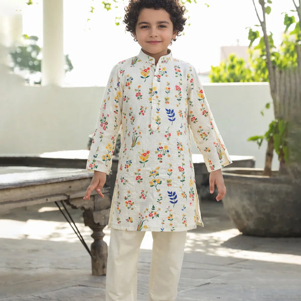 Child wearing a floral embroidered kurta with white pants outdoors.