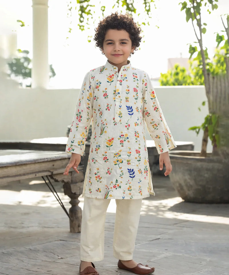Child wearing a floral embroidered kurta with white pants outdoors.