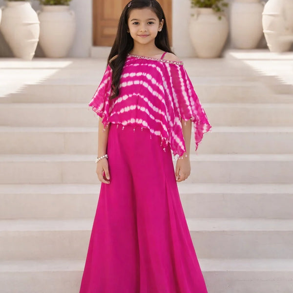 Young girl in a pink tie-dye top and skirt standing on steps with potted plants in the background.