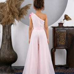 Woman in a pink one-shoulder dress standing in a room with decorative elements.