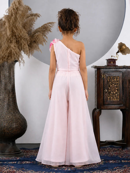 Woman in a pink one-shoulder dress standing in a room with decorative elements.