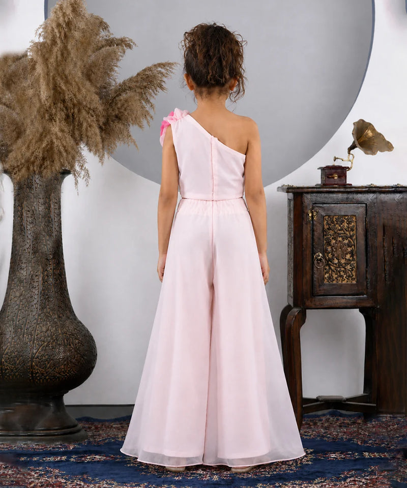 Woman in a pink one-shoulder dress standing in a room with decorative elements.