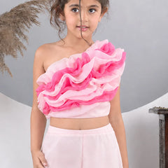 Young girl wearing a pink ruffled top and light pink skirt against a gray background