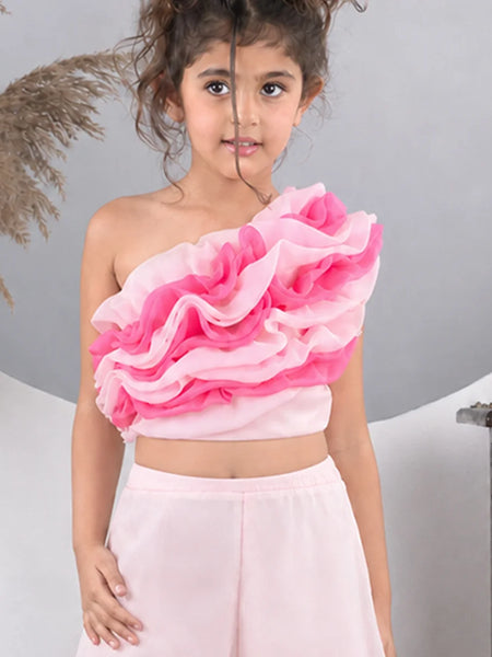 Young girl wearing a pink ruffled top and light pink skirt against a gray background