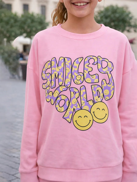 Person wearing a pink sweatshirt with 'Smiley World' design outdoors.