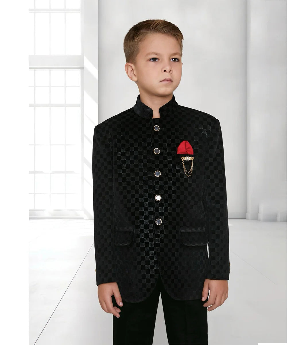  This boys wedding outfit consists of a black Colored self-checked coat and matching pants. It features a broach and a red Colored pocket square.