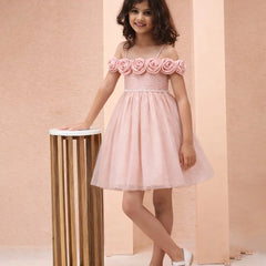 Young girl wearing a pink dress with floral straps against a beige background