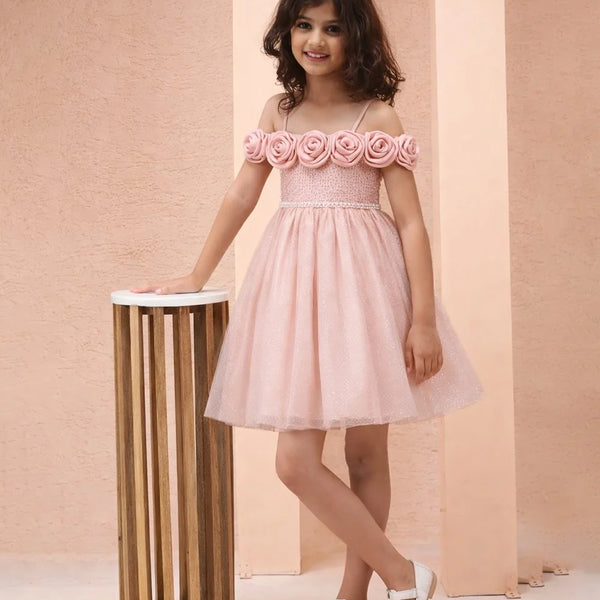 Young girl wearing a pink dress with floral straps against a beige background