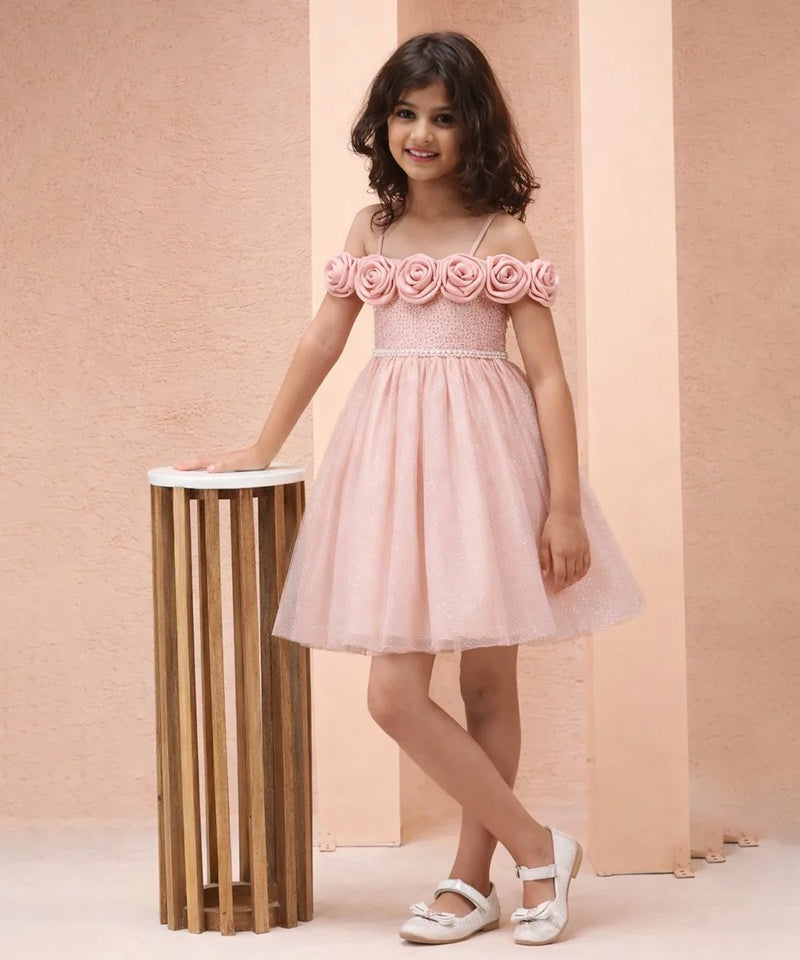 Young girl wearing a pink dress with floral straps against a beige background