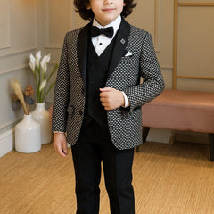 Young boy in a formal suit standing in a room with decorative elements.