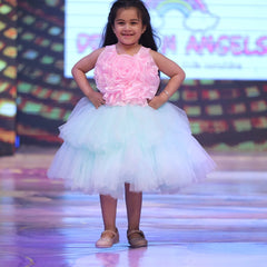 Young girl in a pink and white dress on a stage with colorful background