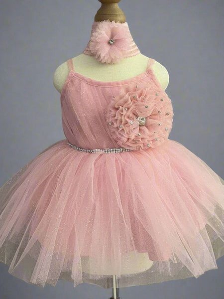 It's a peach Colored frock that features shinny lace, big flower and pleated detailing. Moreover, it comes with an attached belt to be tied at the back.