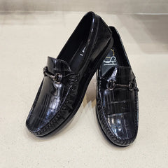 Pair of black patent leather loafers on a light gray background