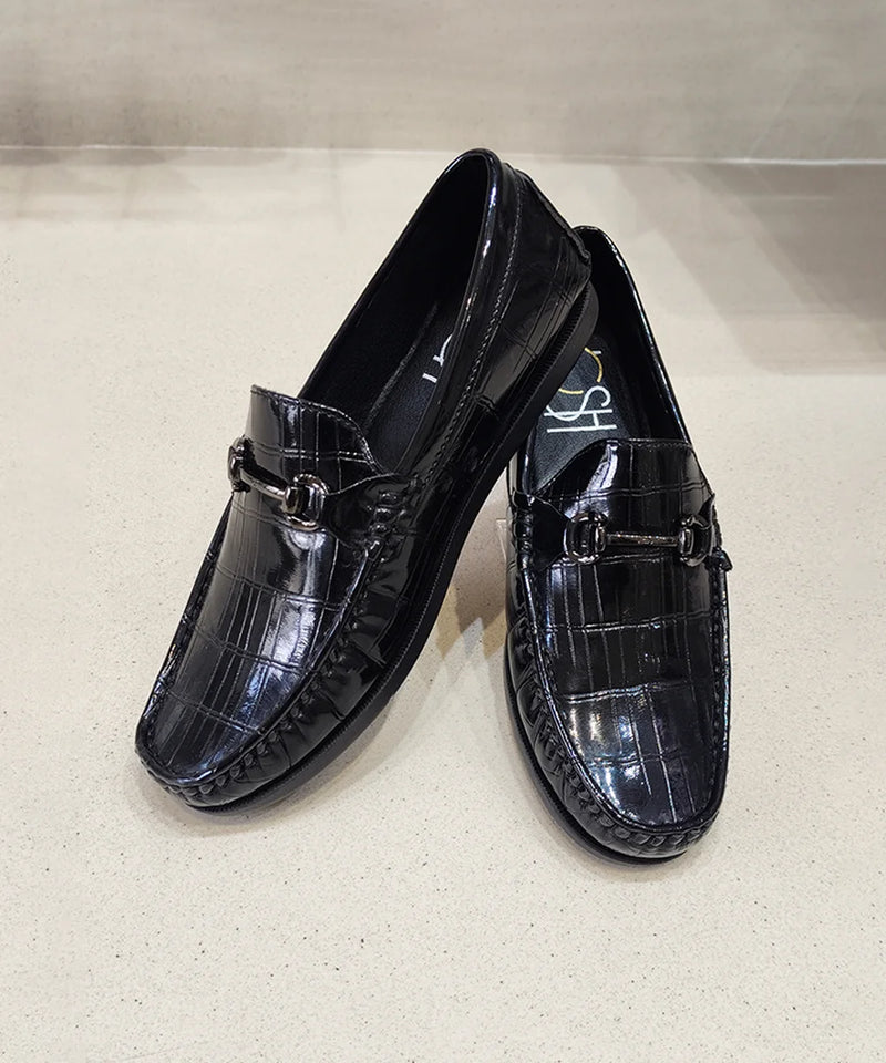 Pair of black patent leather loafers on a light gray background