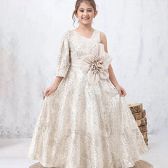 Young girl in a white floral dress with a large flower accessory, standing on a white background.