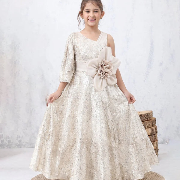 Young girl in a white floral dress with a large flower accessory, standing on a white background.