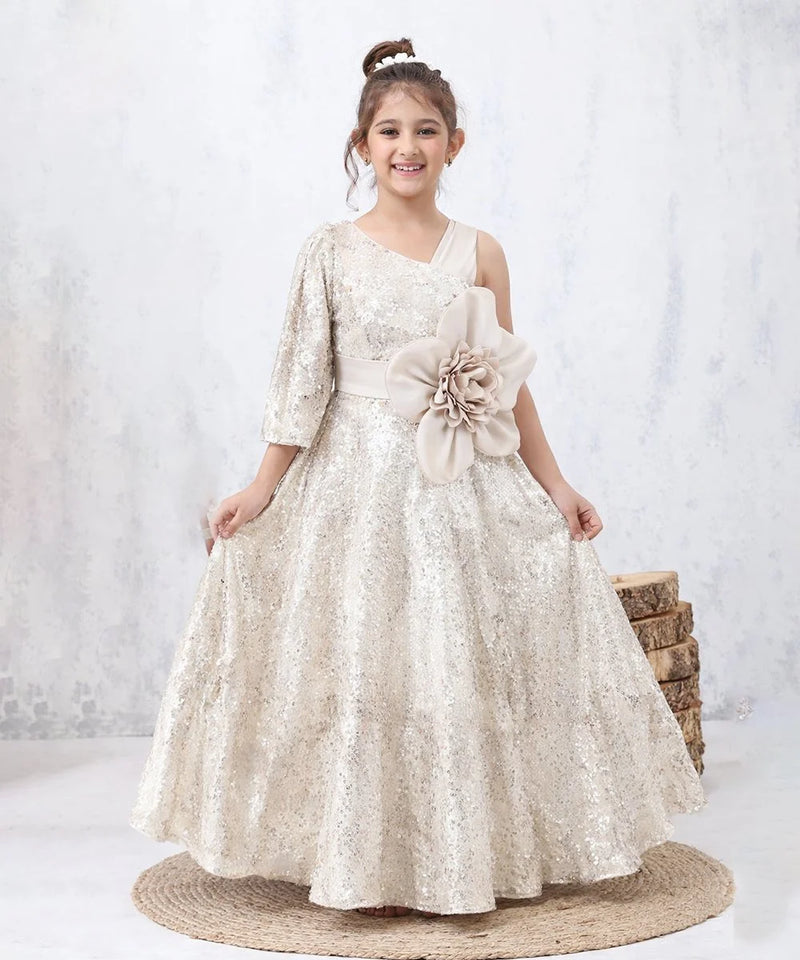 Young girl in a white floral dress with a large flower accessory, standing on a white background.