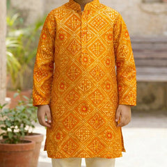 Child wearing a bright orange traditional kurta with intricate patterns, standing outdoors.