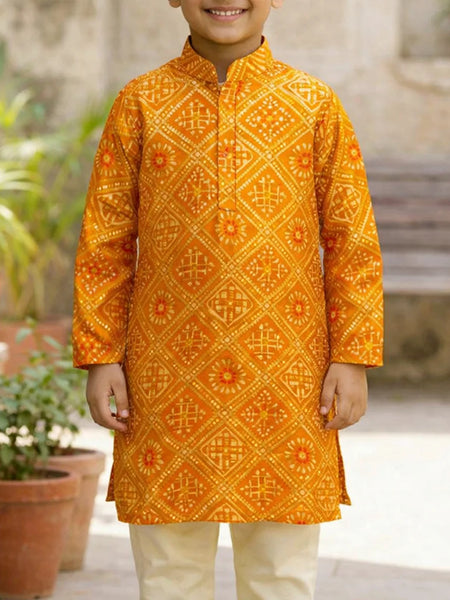 Child wearing a bright orange traditional kurta with intricate patterns, standing outdoors.
