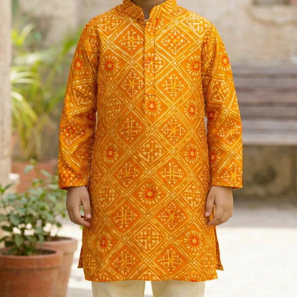 Child wearing a bright orange traditional kurta with intricate patterns, standing outdoors.