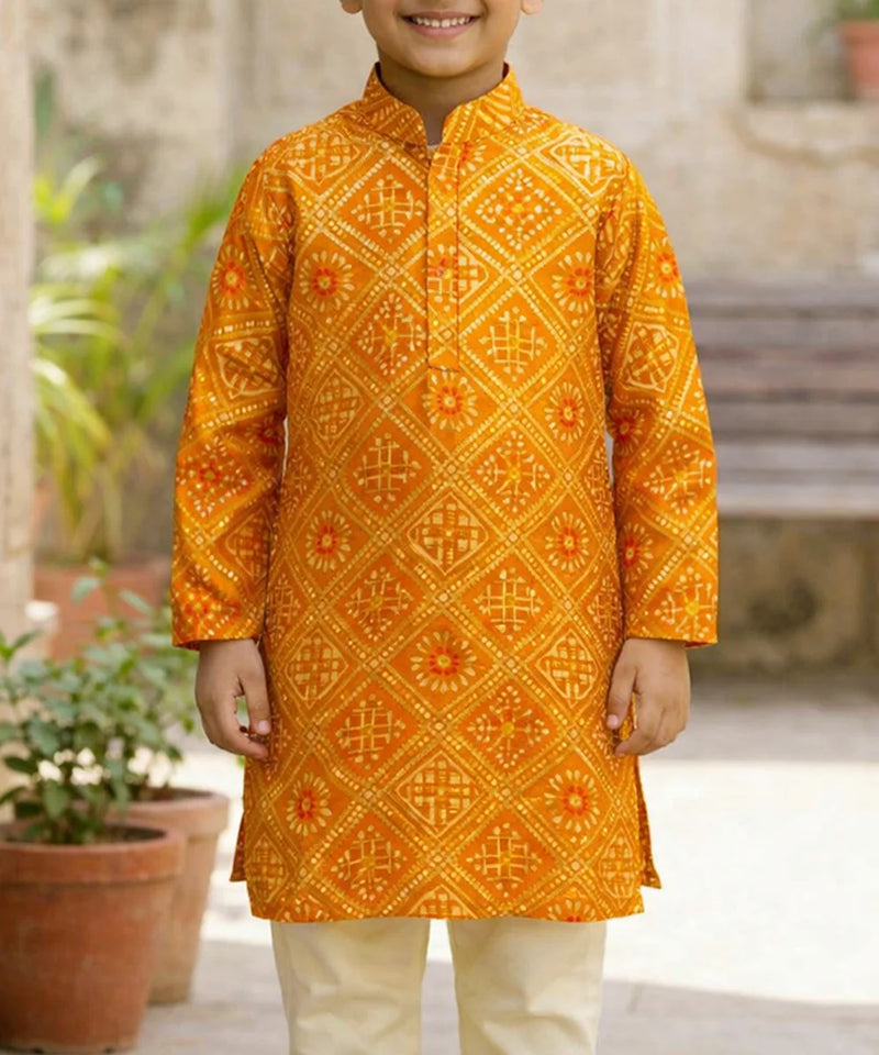 Child wearing a bright orange traditional kurta with intricate patterns, standing outdoors.
