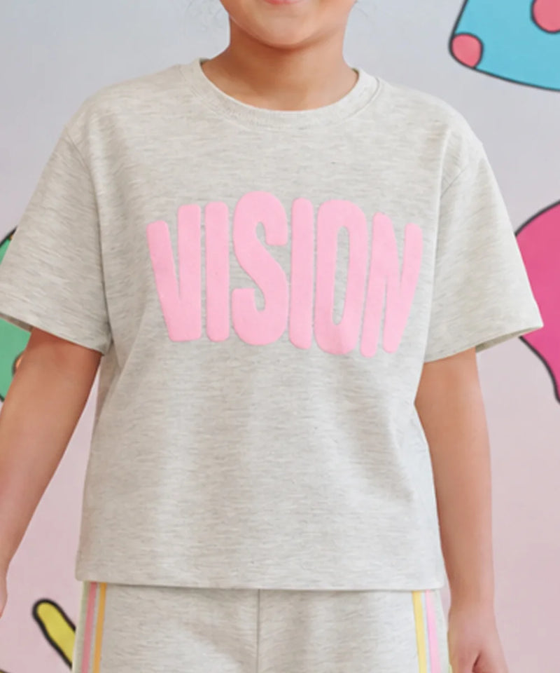 A child wearing a light heather gray short-sleeve t-shirt with the word 'VISION' printed across the chest in large pink letters, paired with matching heather gray pants with thin colored stripes.