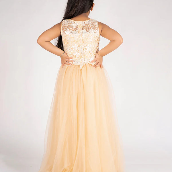 Woman wearing a long, light-colored dress with a lace top on a plain background