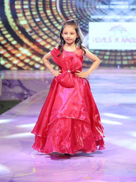 Young girl in a red birthday gown on a stage with a colorful background