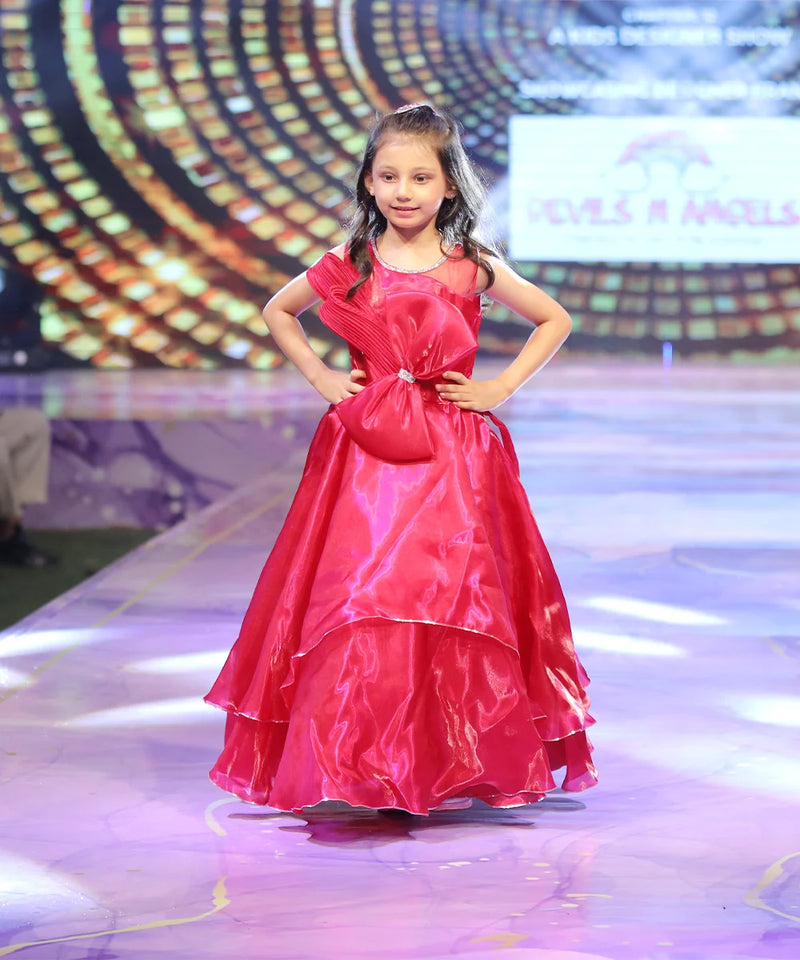 Young girl in a red birthday gown on a stage with a colorful background