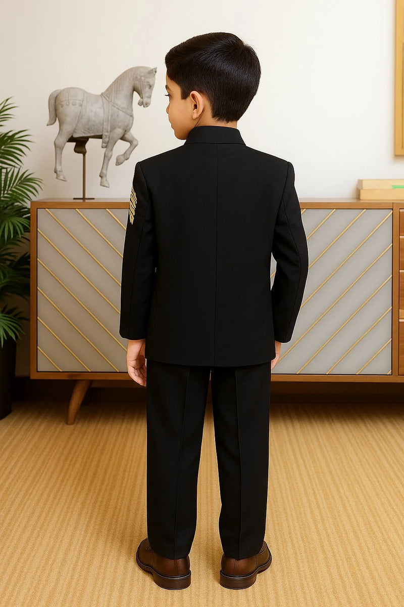 Child wearing a black suit standing in a room with a decorative horse sculpture in the background.