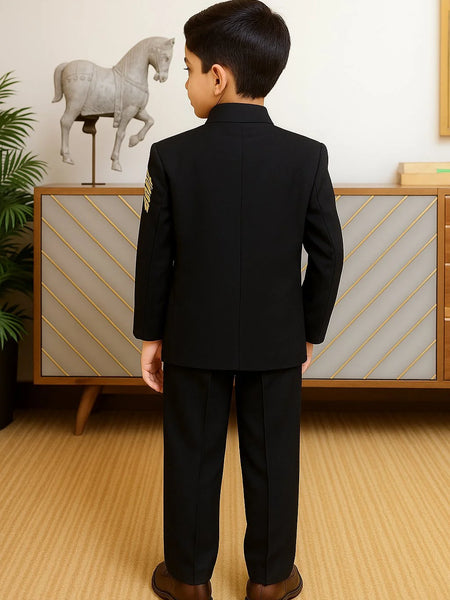 Child wearing a black suit standing in a room with a decorative horse sculpture in the background.